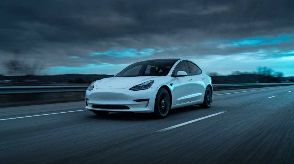 White Tesla Model 3 driving on a highway with motion blur
